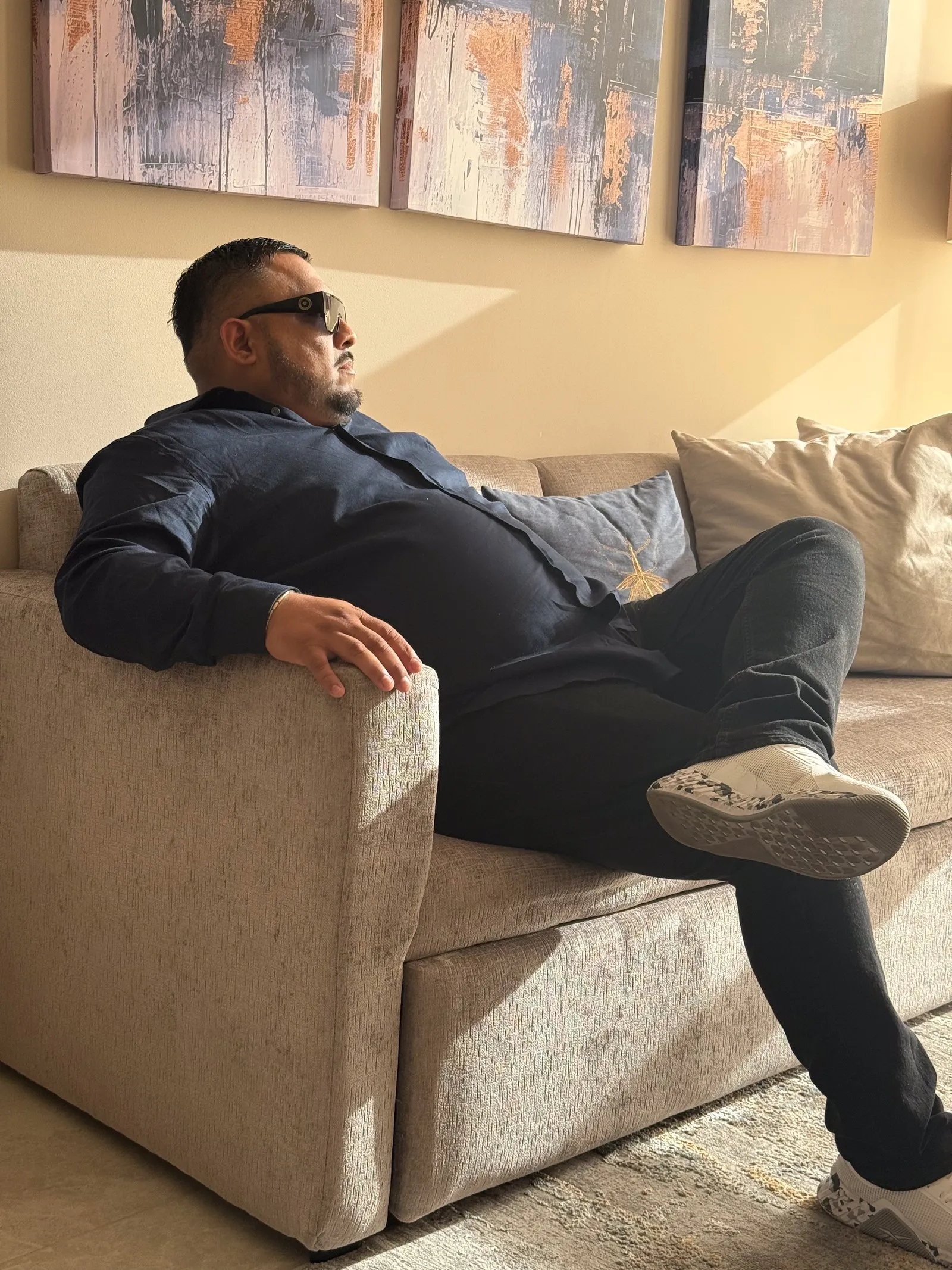 Marco Uribe sentado en un sillón, con camisa azul marino y lentes oscuros, de perfil.